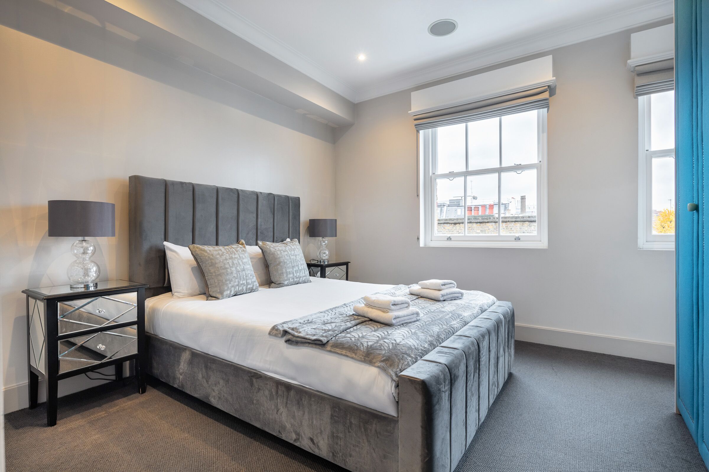 A modern bedroom with a large bed, bedside tables, and a window with a view.