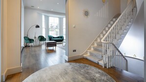A spacious living area with a staircase, a dining area with chairs, and a view through a large window. - *| Perfectly Splendid Triplex House in Chelsea |*
 (London)