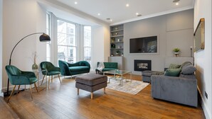 A modern living room with green and grey sofas, a coffee table, and a fireplace. - *| Perfectly Splendid Triplex House in Chelsea |*
 (London)