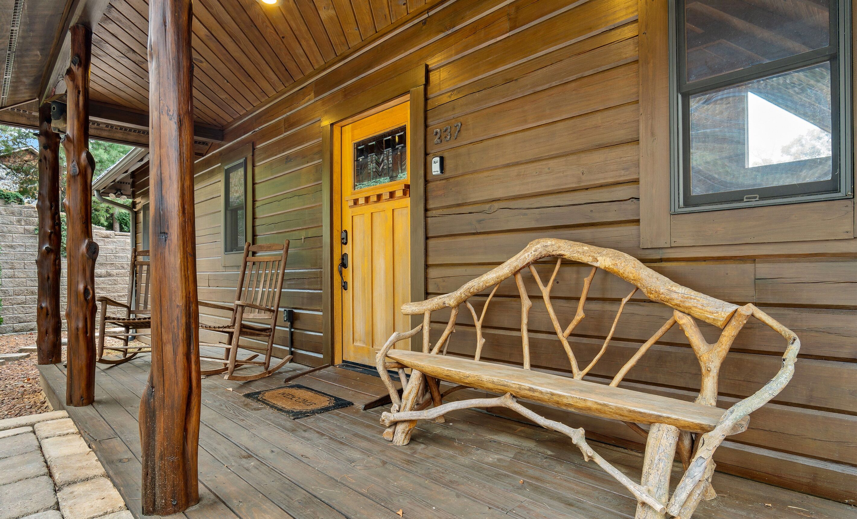 Eine Holzhütte mit Veranda, Schaukelstuhl und Bank.