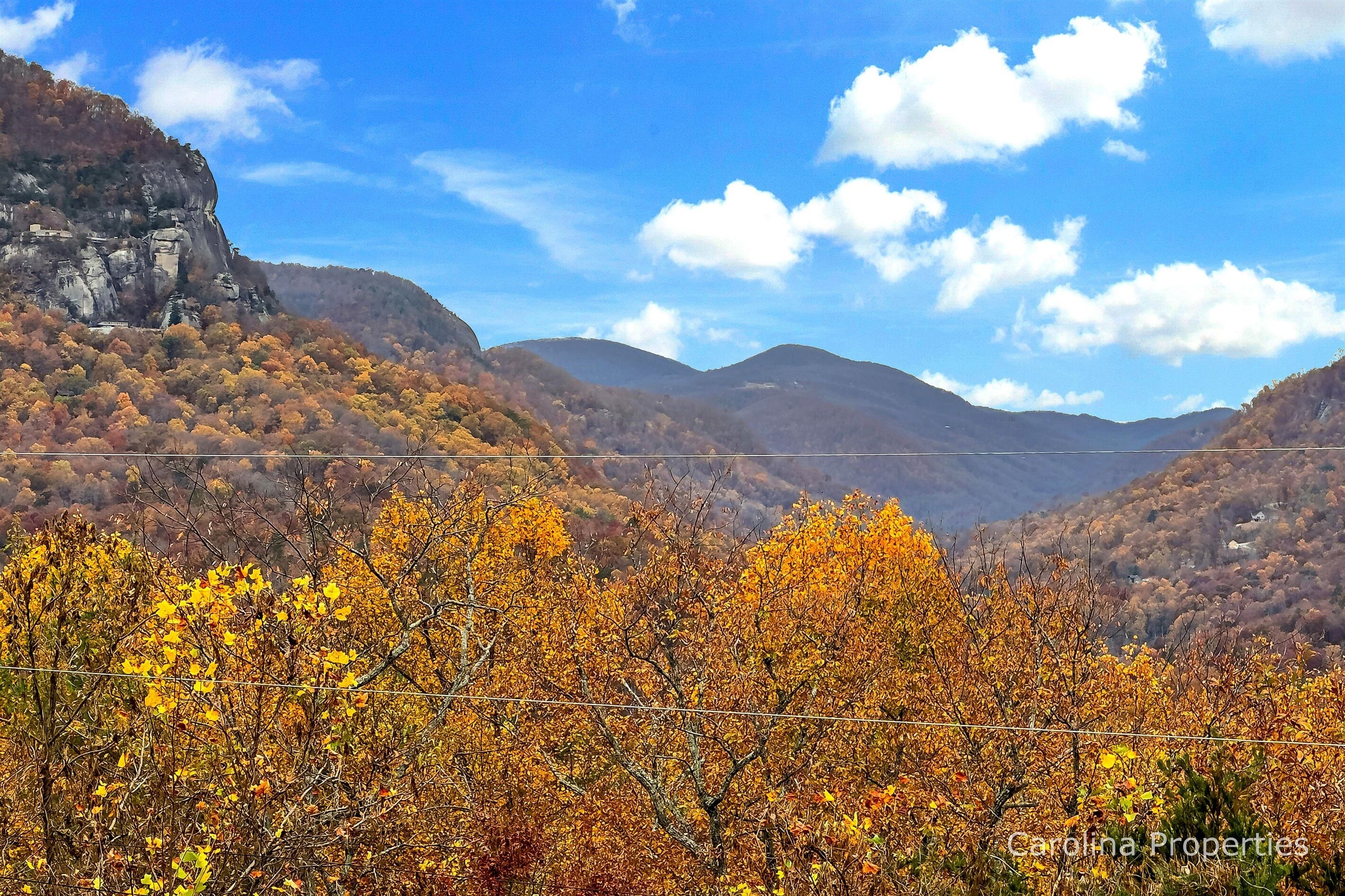 Un paisaje montañoso con follaje otoñal y cielo despejado.