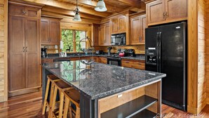 Eine großzügige Küche mit Holzausstattung, Granit Arbeitsplatten und Edelstahlgeräten.