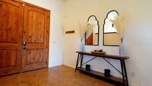 A wooden door, a console table with vases, and a mirror on the wall.