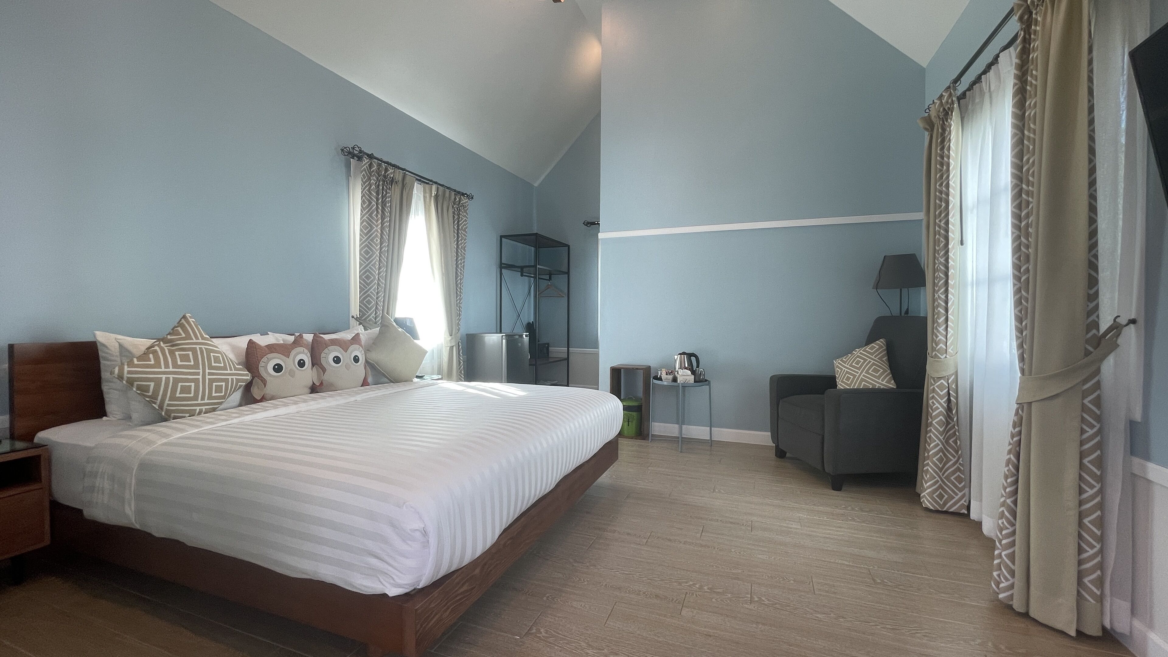 Ein Schlafzimmer mit einem großen Bett, einem Sessel, einem kleinen Tisch und einem Kleiderschrank.
