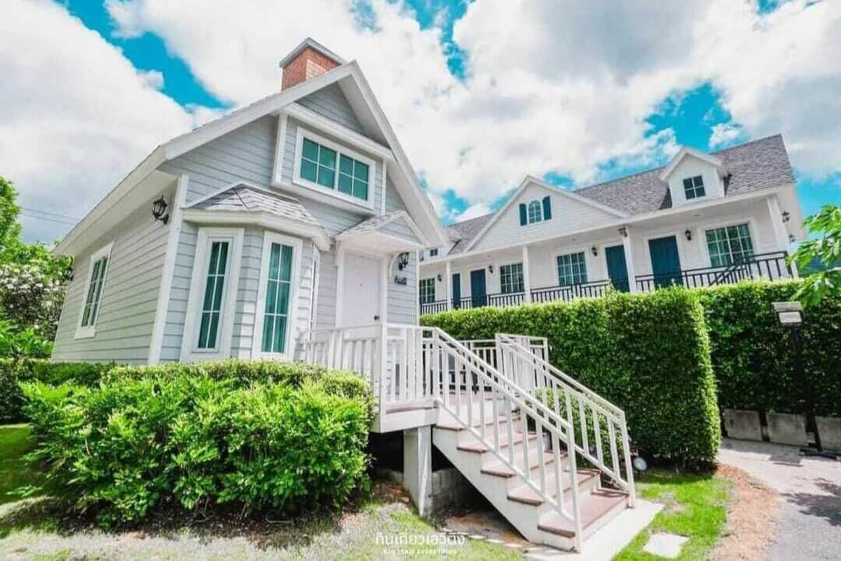 A two-story house with a staircase leading to a porch.