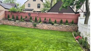 A well-maintained backyard with a stone retaining wall, a lawn, and a variety of shrubs and plants. - Adorable 1 bedroom mins away to NYC in Teaneck

 (Teaneck)