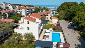 Un quartier résidentiel avec une piscine, une route et un port de plaisance en arrière-plan.