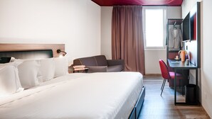 A hotel room with a large bed, a desk, a chair, a TV, and a wardrobe. - CX Venice Mestre (Mestre)