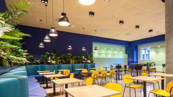 A modern dining area with blue seating, yellow chairs, and multiple tables.