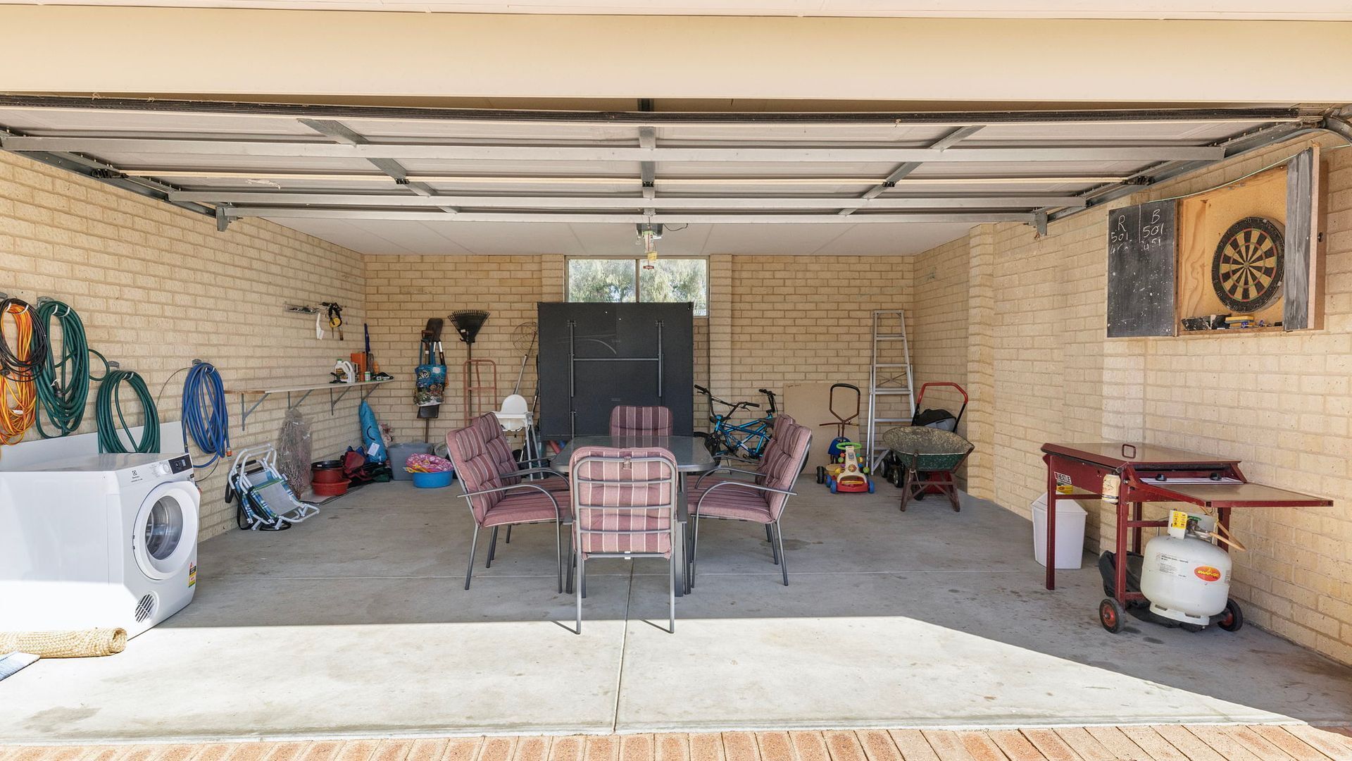 A garage with a dining area, a washing machine, and a dartboard.