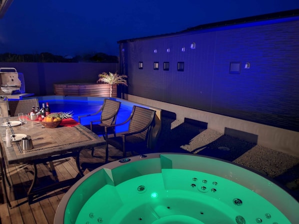 Une terrasse extérieure dotée d’un jacuzzi, d’un espace salon et d’un barbecue.