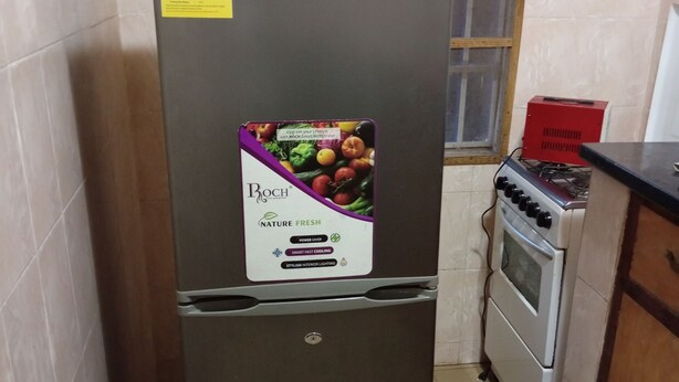 A refrigerator with a sticker advertising energy efficiency and a window above it. - Annex House For Rent (Serrekunda)