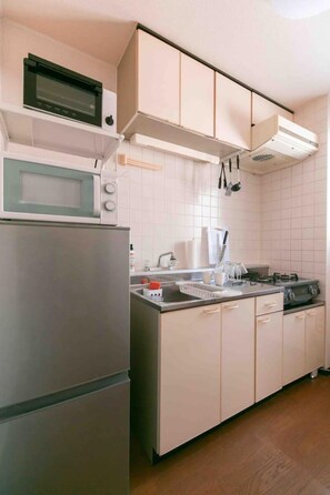 Een koelkast, een magnetron, een kookplaat, kookgerei, borden en bestek