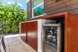Eine Küche mit einem eingebauten Edelstahlkühlschrank, Holzschränken und einem Fenster mit Blick auf einen Garten.
