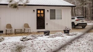 A small cabin with a dark door, two chairs outside, and a car parked nearby. - Modern Bungalow - Endless Recreation, Close to TV (Traverse City)
