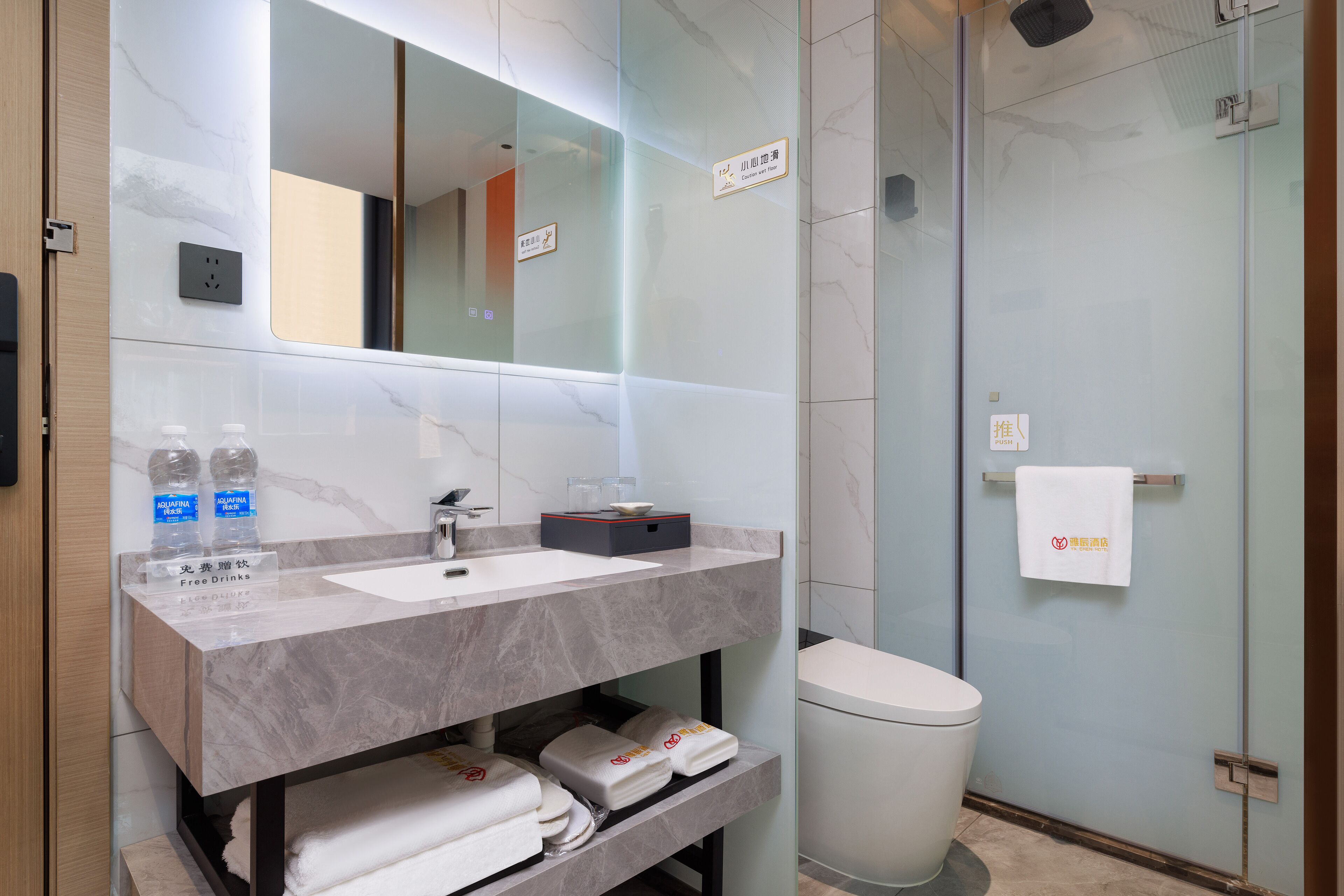 A modern bathroom with a marble vanity, a glass shower enclosure, and a white toilet.