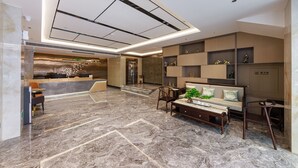 A modern lobby with a marble floor, a reception desk, seating area, and a staircase. - Ya Chen Hotel (Guangzhou)