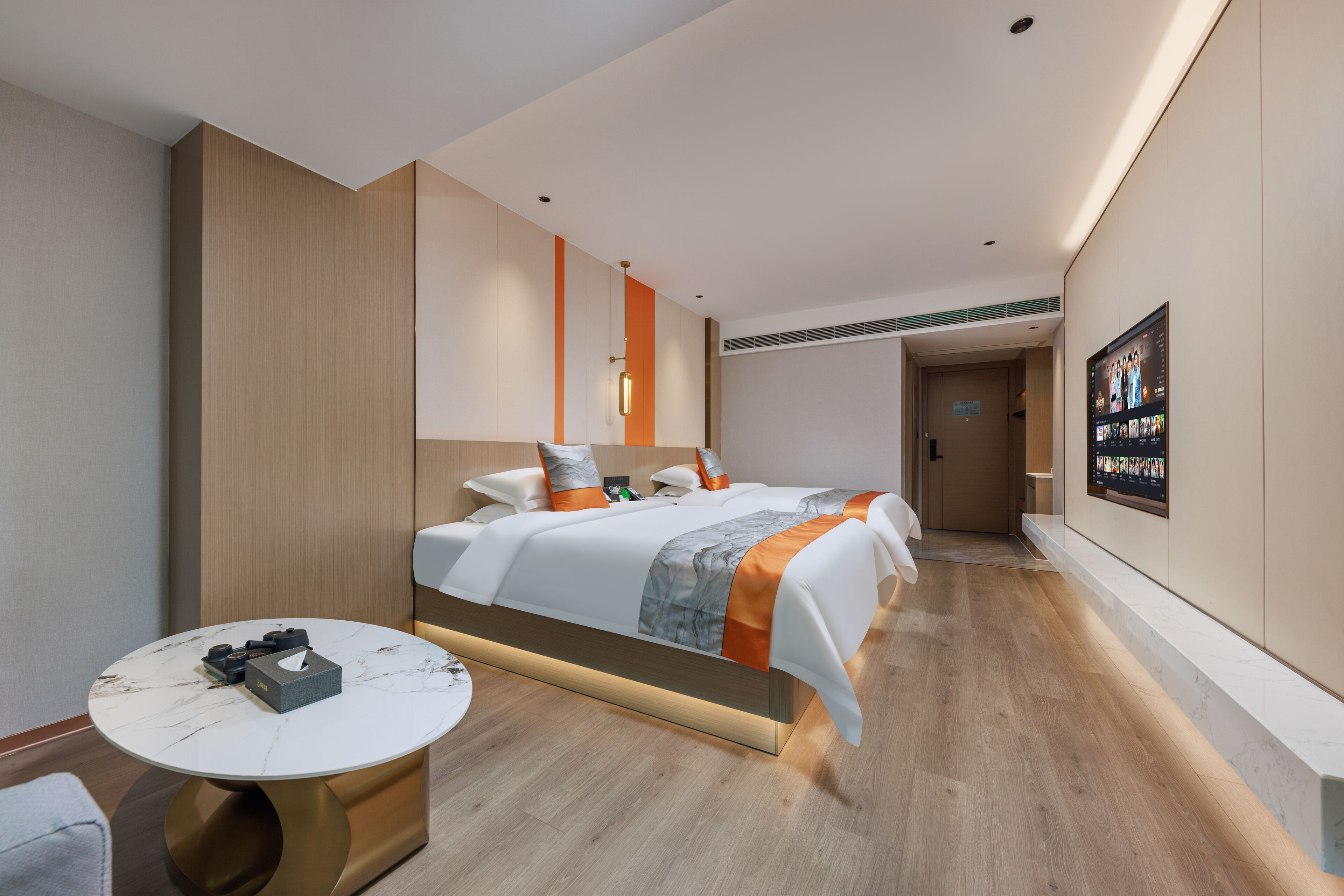 Habitación de hotel moderna con una cama grande, una mesa redonda y un televisor fijado a la pared.