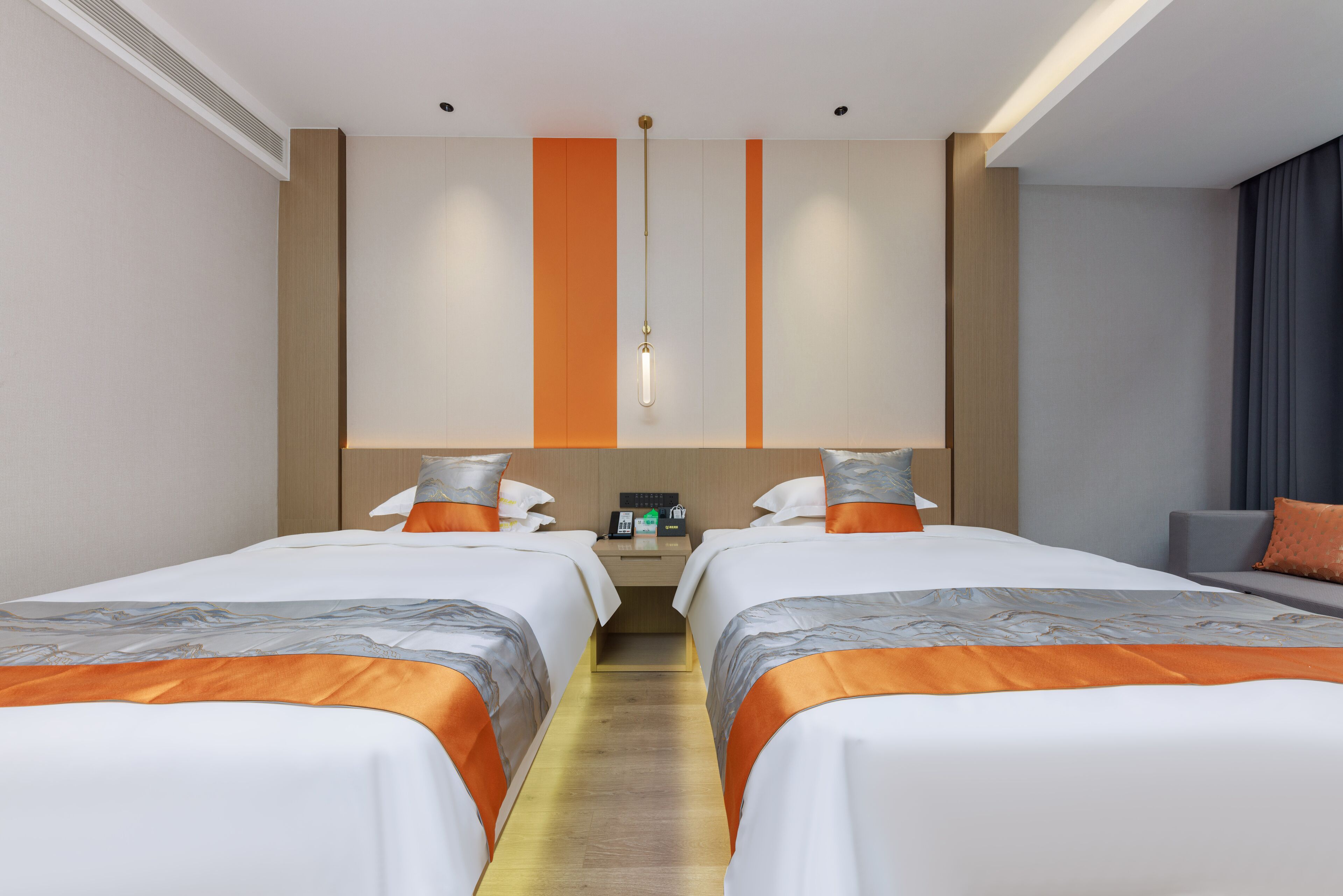 A hotel room with two beds, a nightstand, a desk, and a seating area.