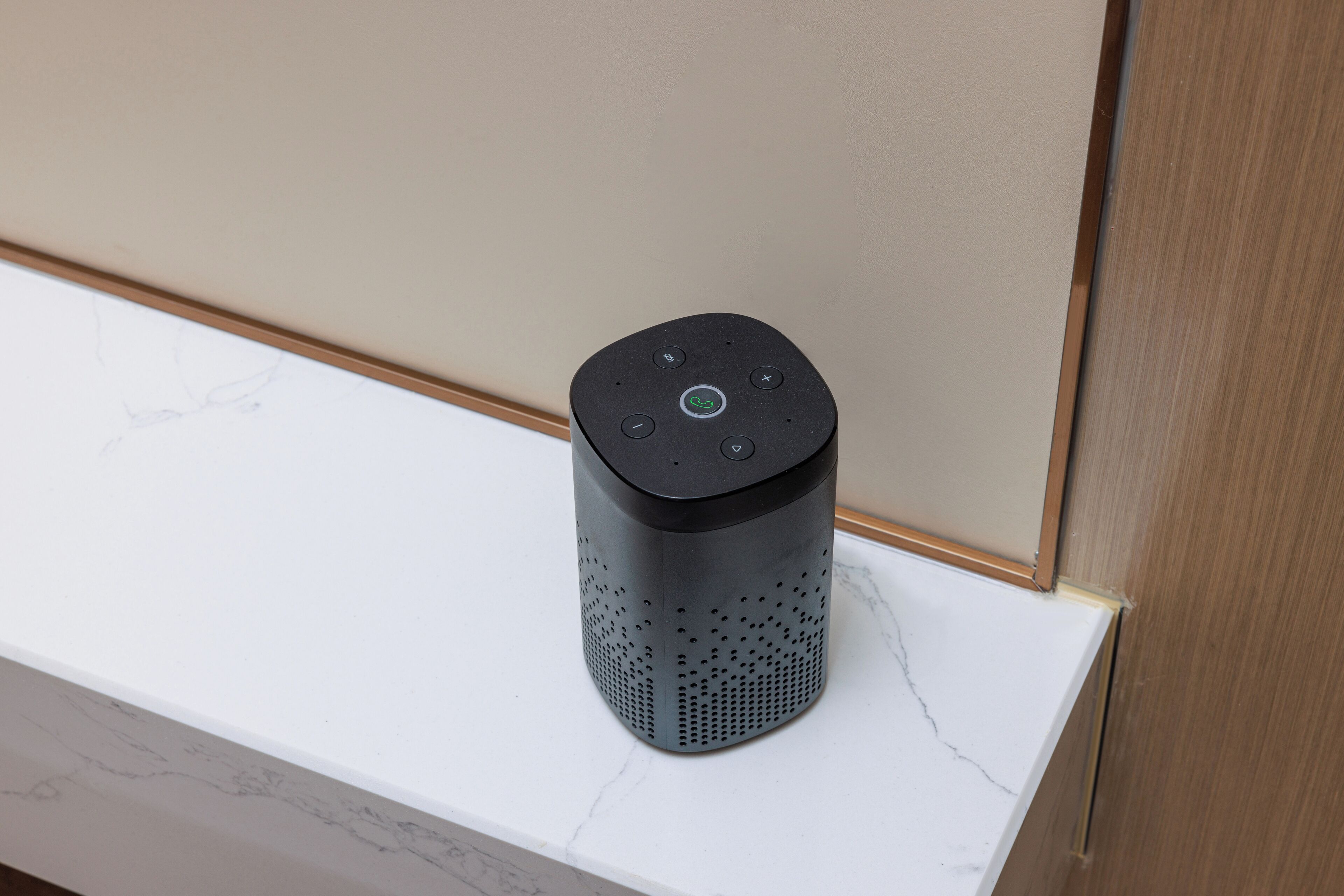 A smart speaker on a white marble countertop.