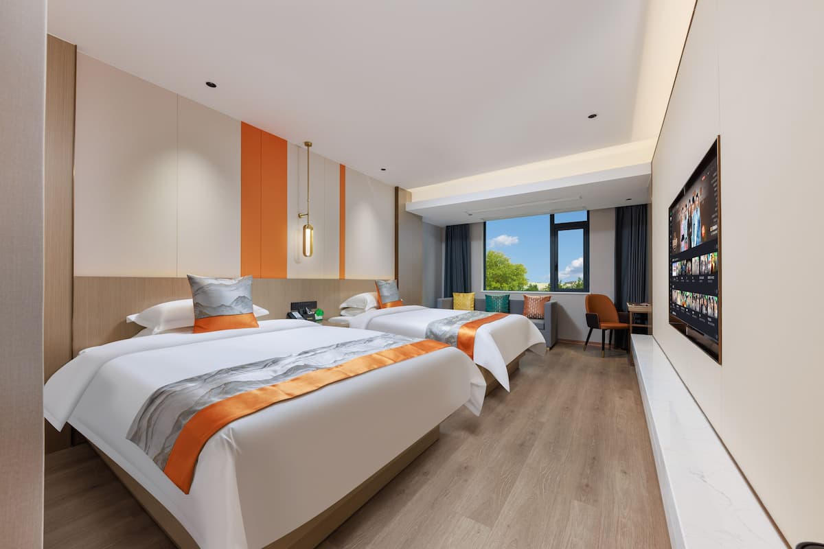 Une chambre d’hôtel avec deux lits, un bureau et une grande fenêtre.