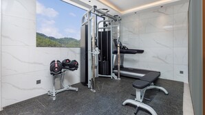 A gym with a bench, weight rack, and a wall-mounted exercise machine. - Ya Chen Hotel (Guangzhou)