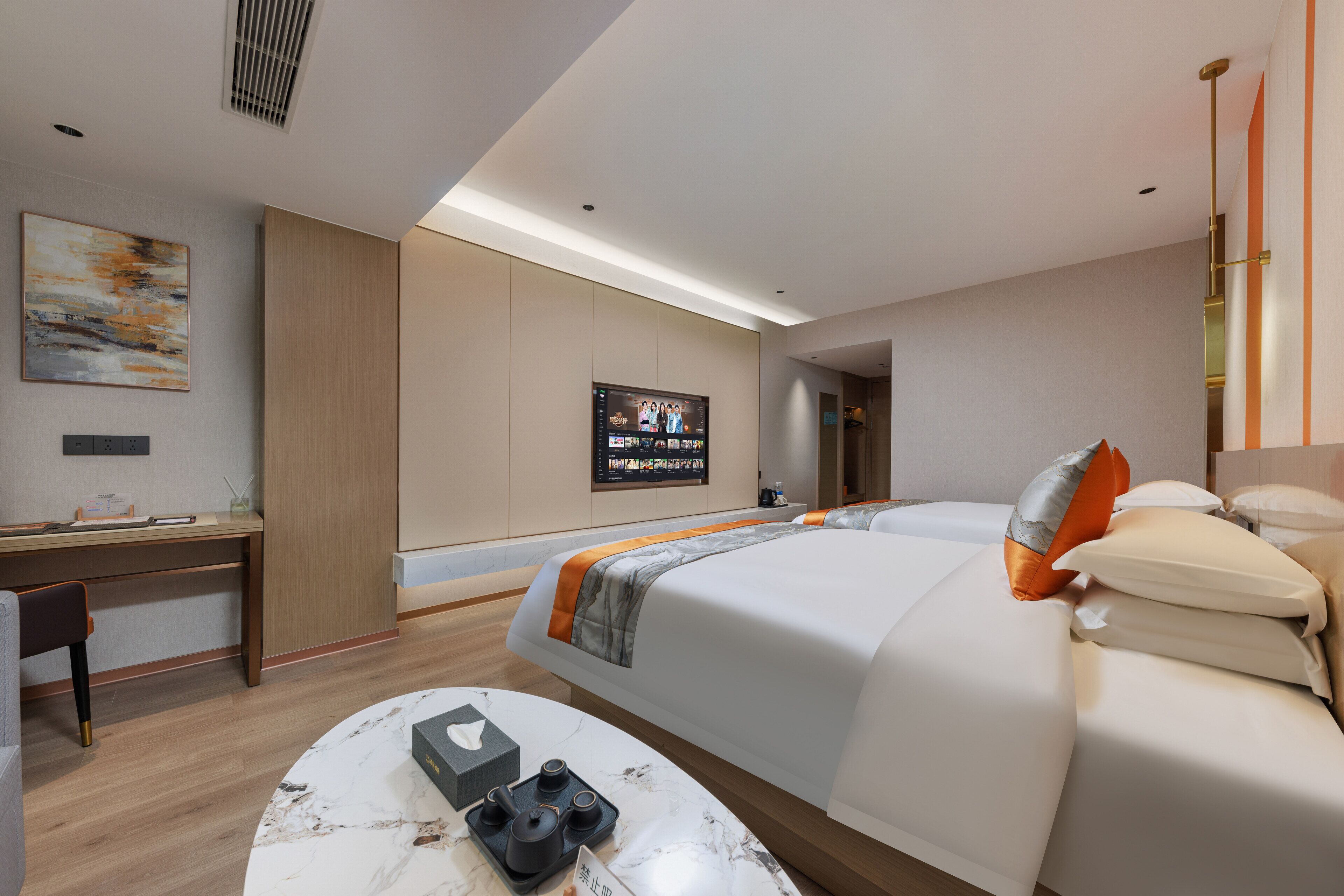 A modern hotel room with a large bed, a desk, and a TV mounted on the wall.