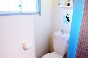 A small bathroom with a toilet, a sink, and a window.