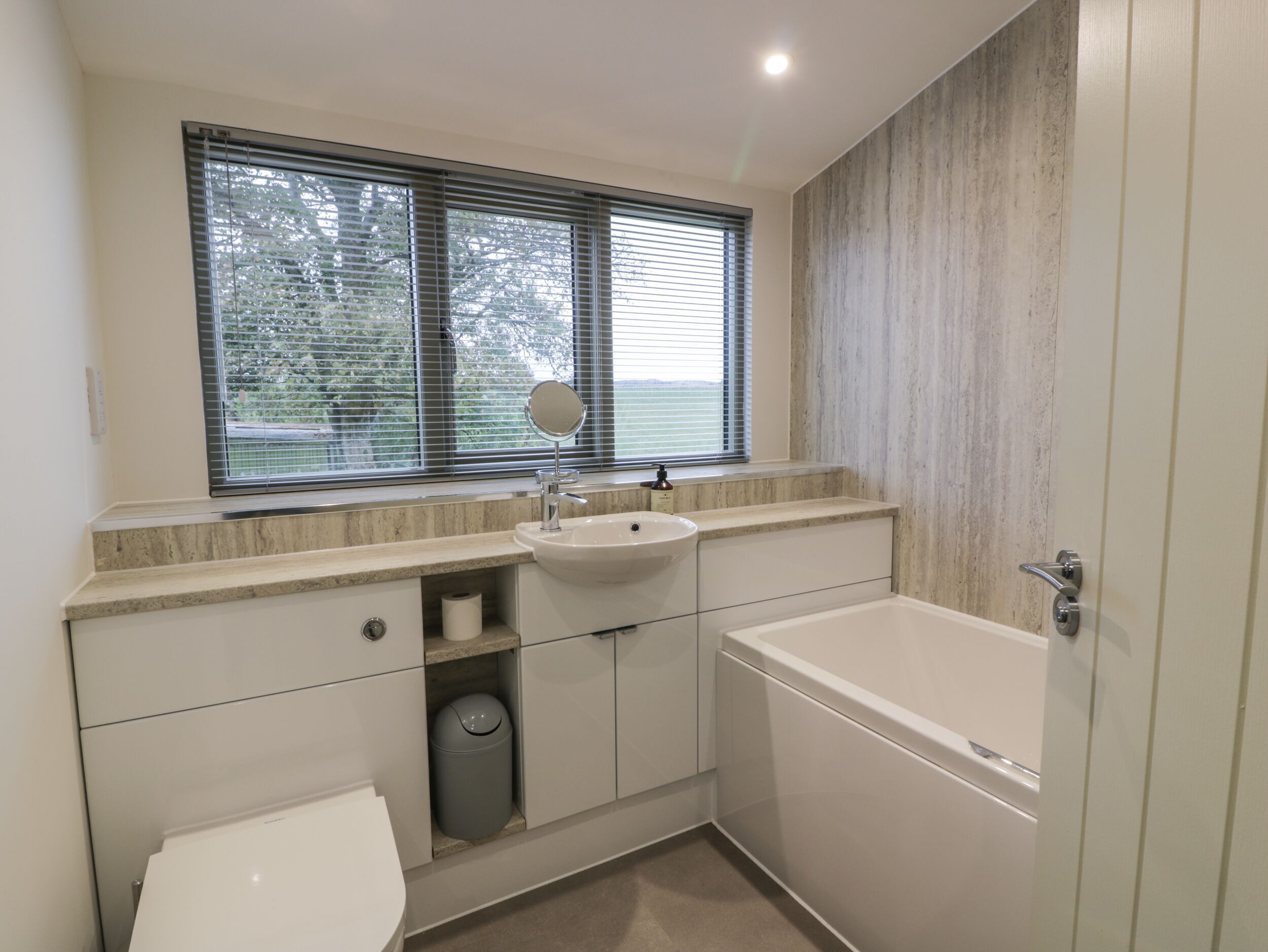 Un baño moderno con lavamanos, espejo, inodoro y bañera.