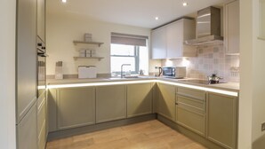 A modern kitchen with light wood cabinets, a built-in oven, and a window with a view. - Thorneydyke Cottage (Stirling)