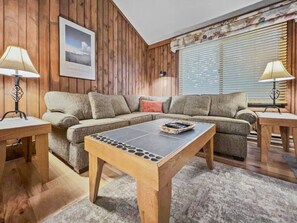 A cozy living room with a sectional sofa, a coffee table, and two lamps.