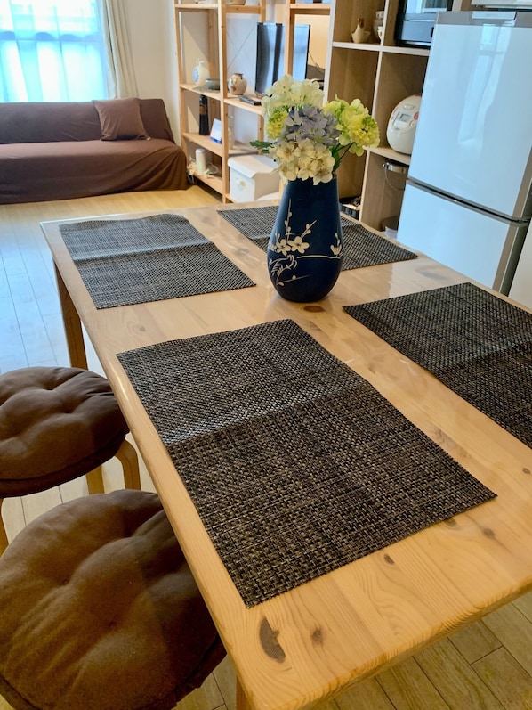 Un tavolo da pranzo con un vaso di fiori, sottopiatti neri e sedute imbottite marroni.
