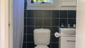 Ett badrum med en toalett, ett handfat och ett fönster ovanför handfatet.