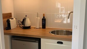 Ett kök med en bänkskiva i trä, en kaffebryggare, en flaska vin och en diskho i rostfritt stål.