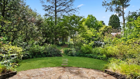Un sentier de jardin menant à un bâtiment dont l’entrée est en pierre.