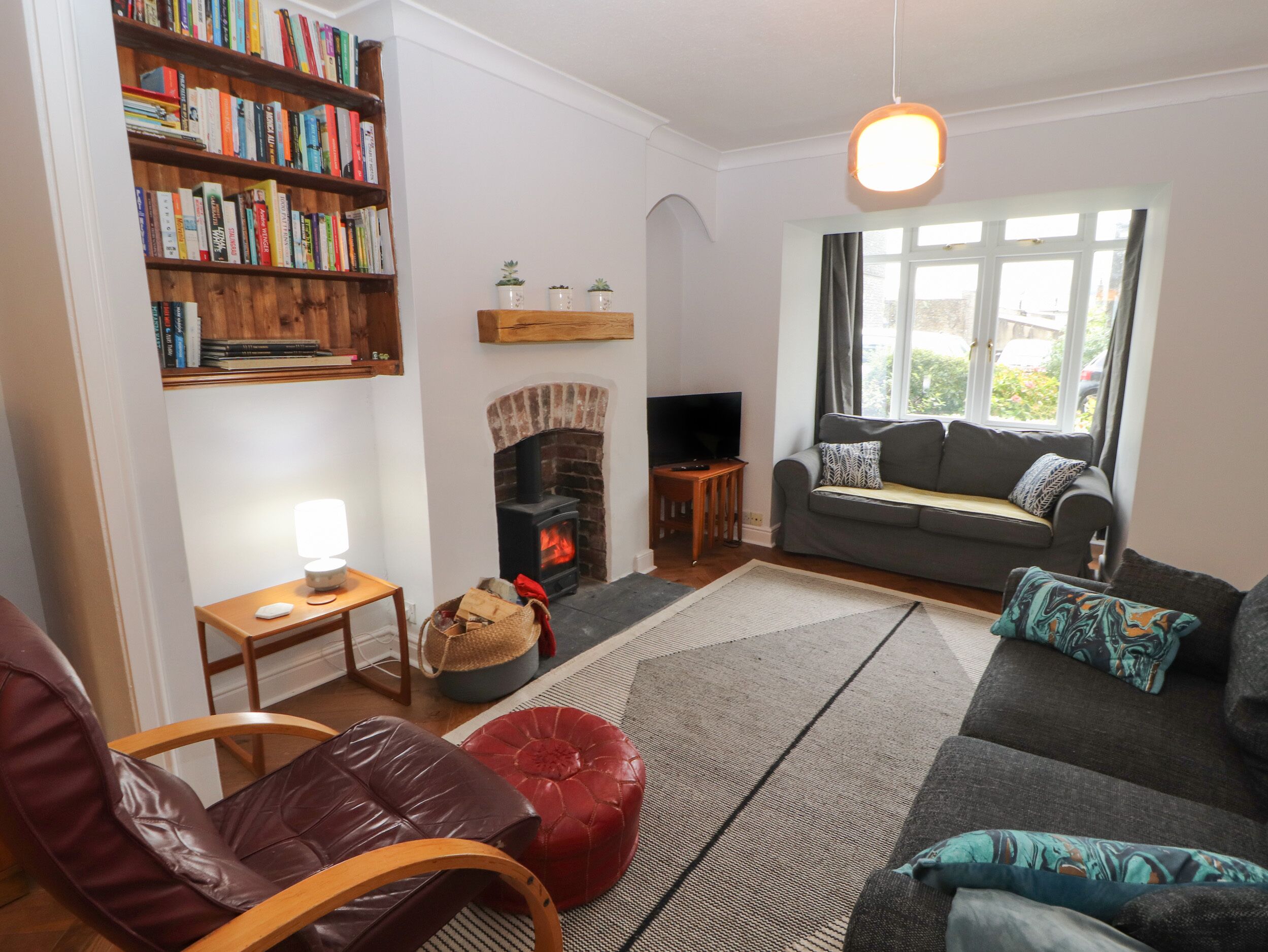 A cozy living room with a fireplace, a bookshelf, a sofa, and a television.