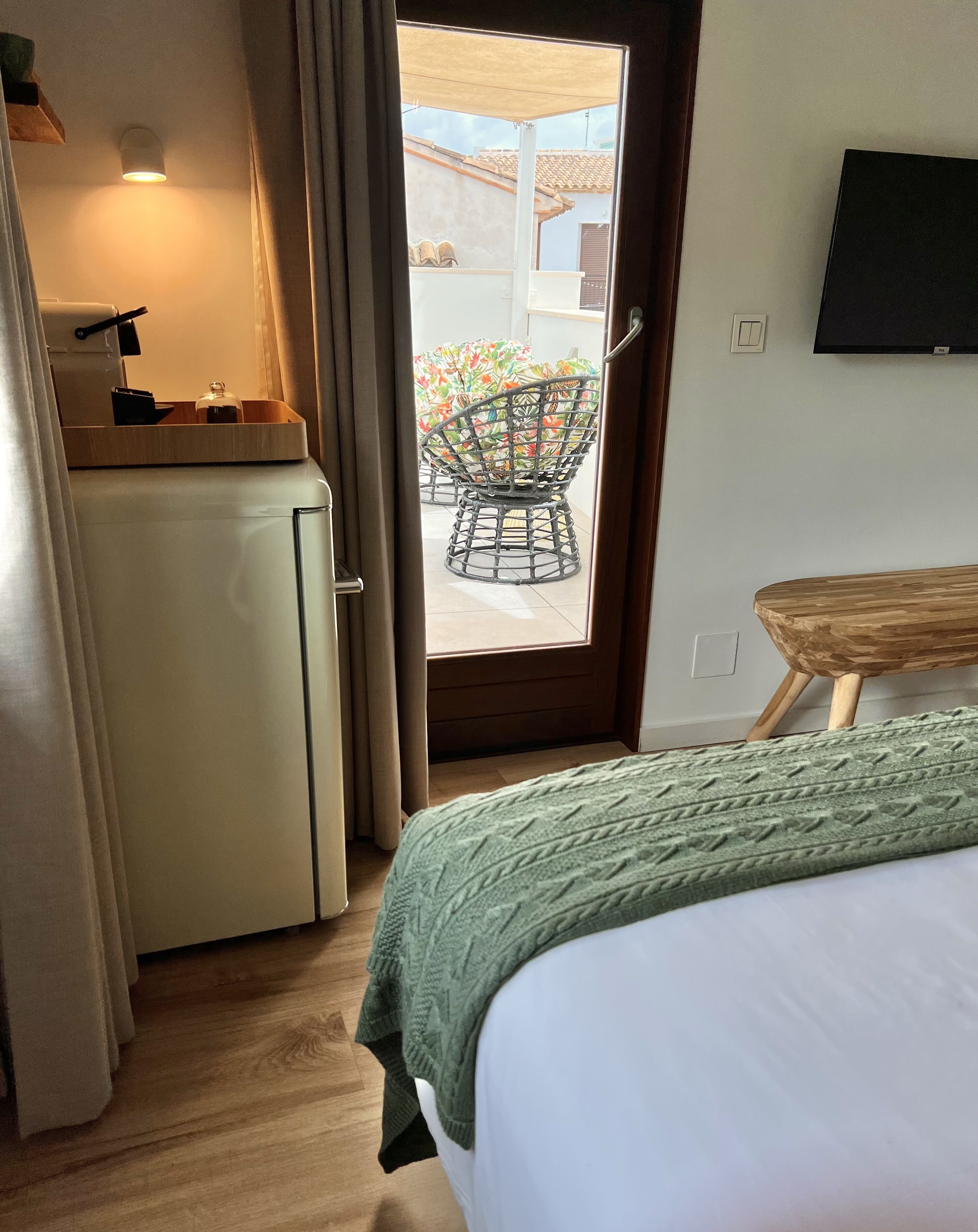A hotel room with a bed, a desk with a computer, a chair, and a small table.