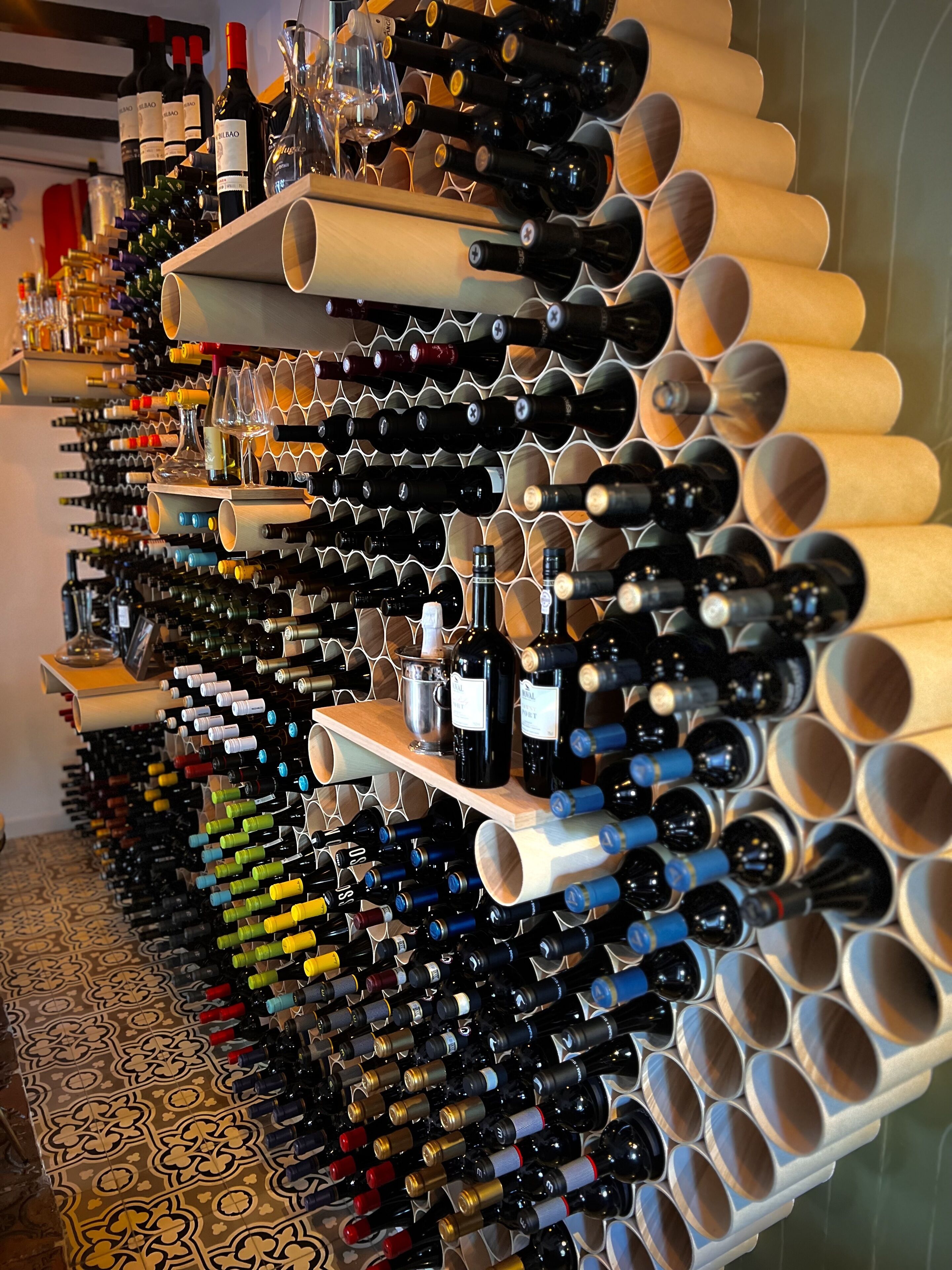 A wine rack with multiple bottles and glasses.