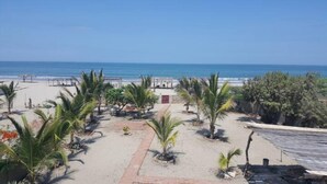 A beach with palm trees, a pathway, and a building with a red door. - Casa de Playa Cahuve Frente al mar (Cardalito)