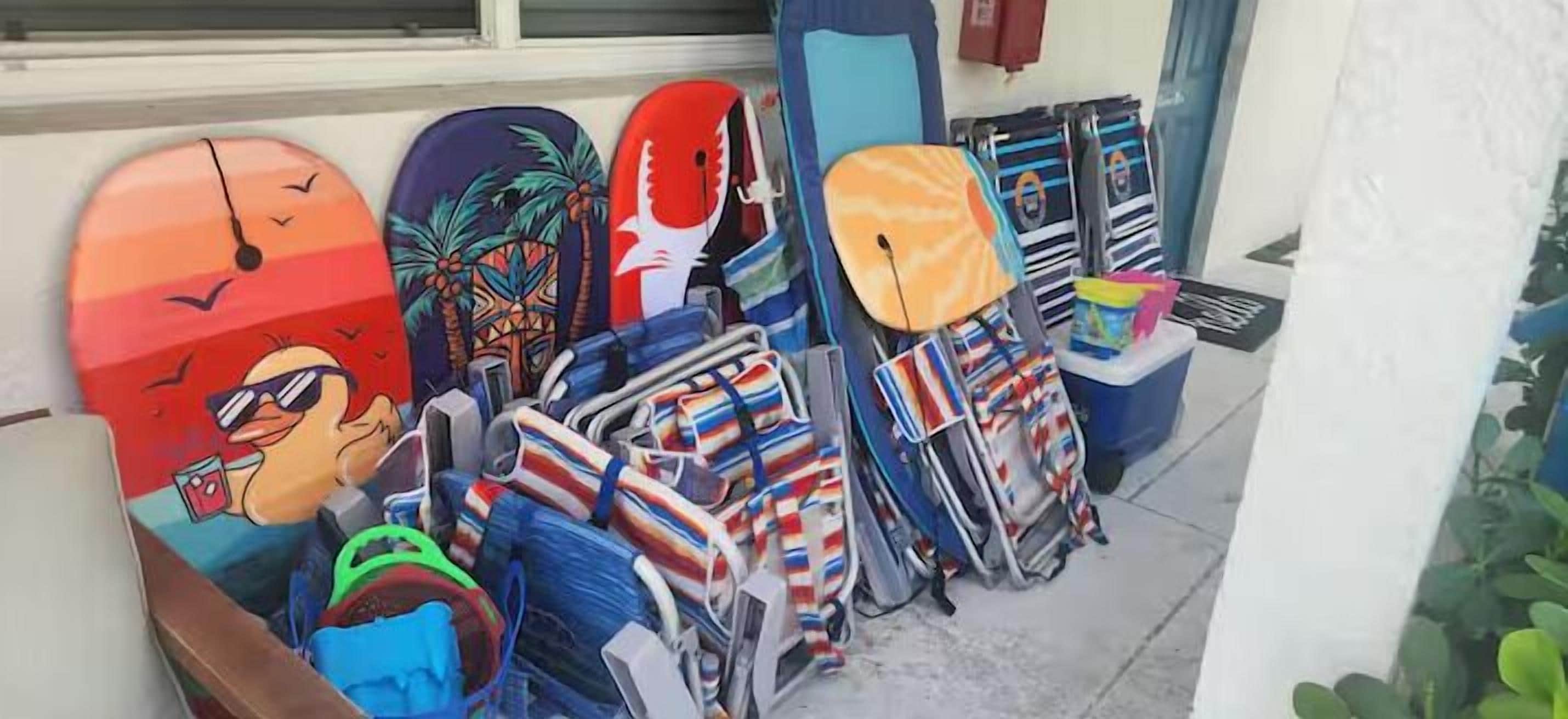 En rad färgglada surfbrädor och ett surfbrädshållare utanför en byggnad.
