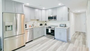 A modern kitchen with stainless steel appliances, white cabinetry, and a central island. - Isla Palma Singer Island (Singer Island)