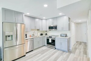 Una cocina moderna con electrodomésticos de acero inoxidable, armarios blancos y una isla central.