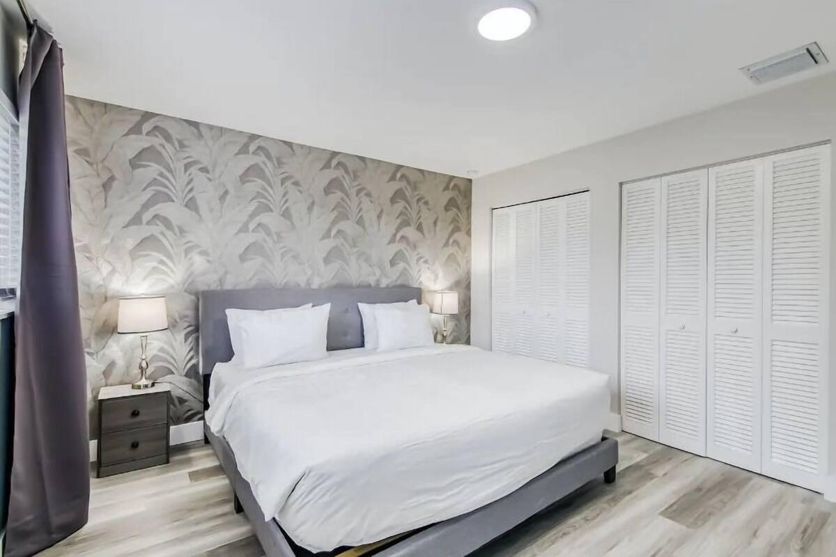 A bedroom with a bed, nightstands, a lamp, and a wardrobe.