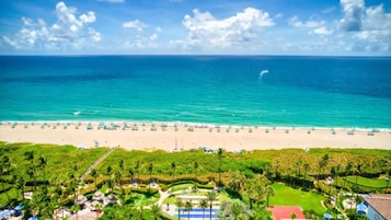 Un resort frente a la playa, con una extensa playa de arena, aguas turquesas cristalinas y abundante vegetación.