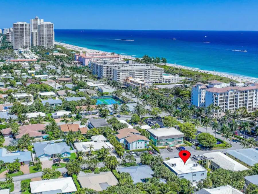 Vista aérea de una zona residencial costera con playa, que incluye edificios de varios pisos y un lugar señalado.