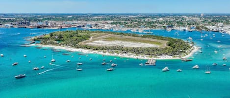 An aerial view of a tropical island with clear turquoise waters, surrounded by a marina with numerous boats.