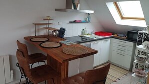Une cuisine de taille réduite, avec une table en bois, quatre chaises, une cuisinière et un four à micro-ondes.