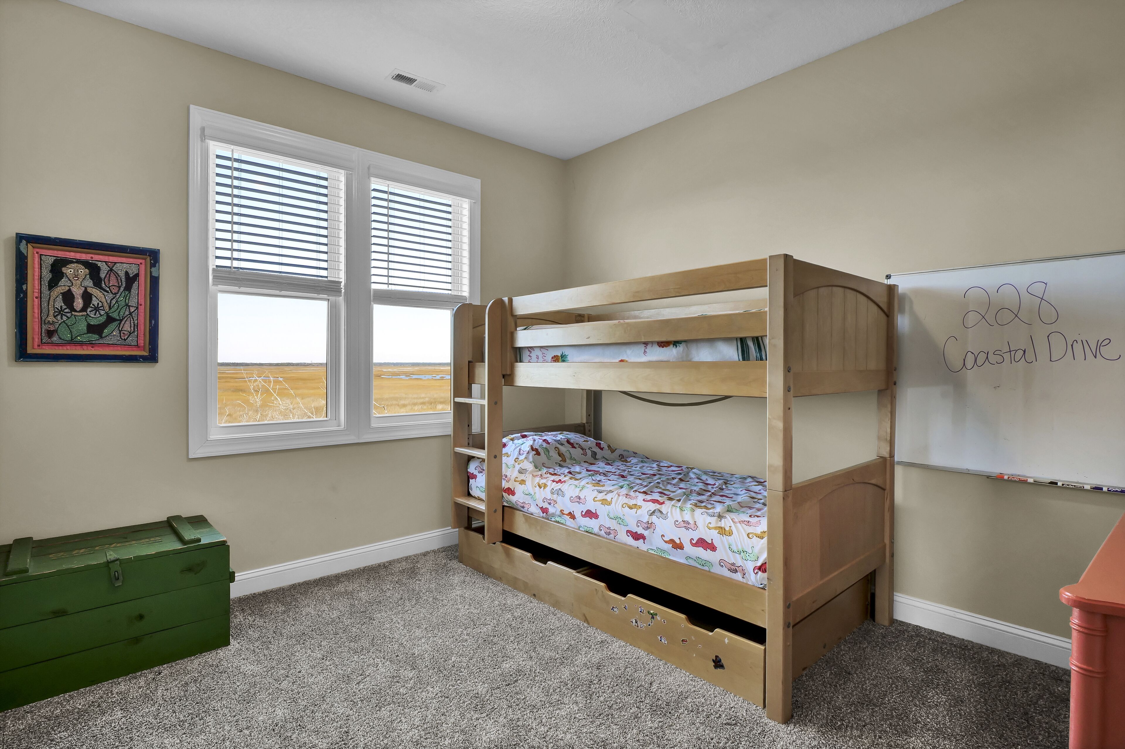 Quarto com beliche, janela, quadro branco e uma caixa de armazenamento verde.