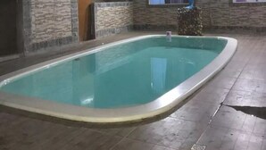 Une piscine avec un mur en pierre et une terrasse en bois.