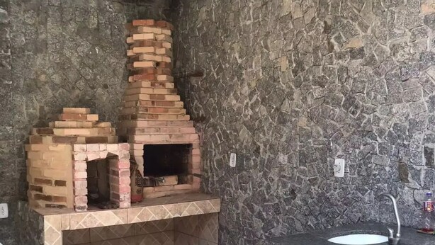 Une salle de bain avec un mur en pierre, un lavabo et un petit four en briques.